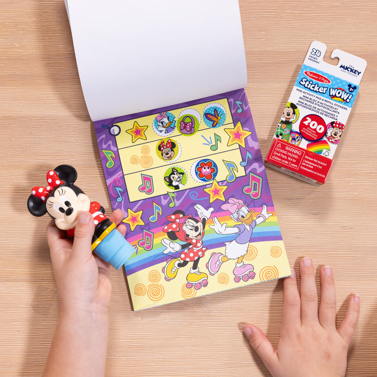 A kid playing with The Melissa & Doug Sticker WOW!™ Disney Minnie Mouse Bundle: 24-Page Activity Pad, Sticker Stamper, 500 Stickers, Mini Pad, Arts and Crafts Fidget Toy Collectible Character