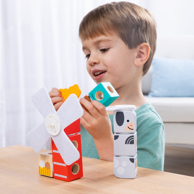 A kid playing with The Melissa & Doug Blockables™ Farm and Farm Friends 2-Pack Bundle Connectable Wooden Building Blocks Preschool Play Set Toy