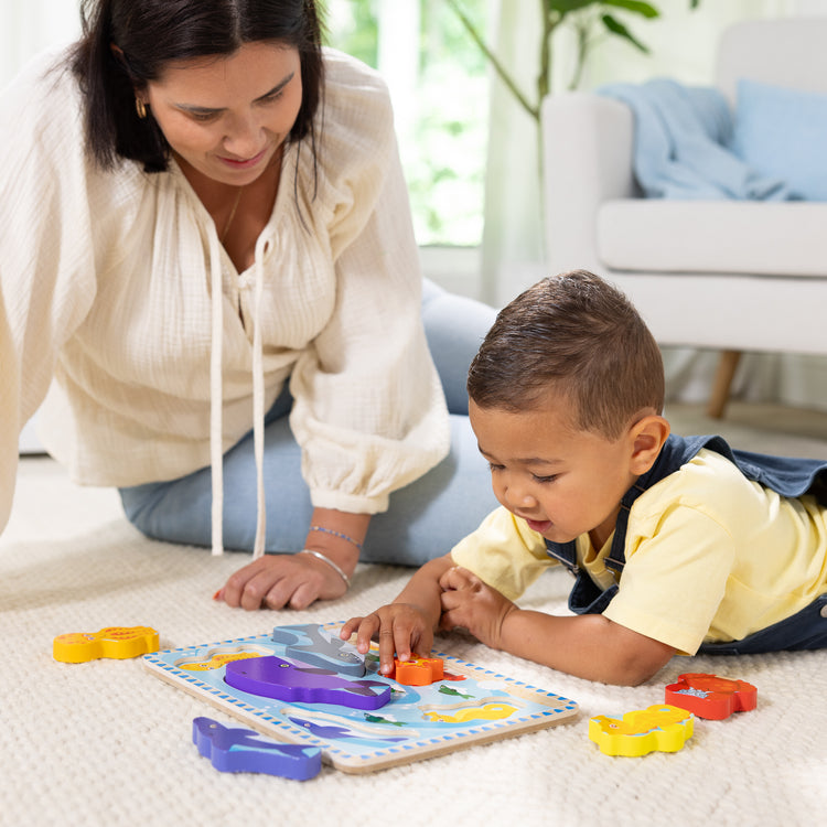A kid playing with The Melissa & Doug Sea Creatures Ocean Wooden Chunky Puzzle - 7 Pieces