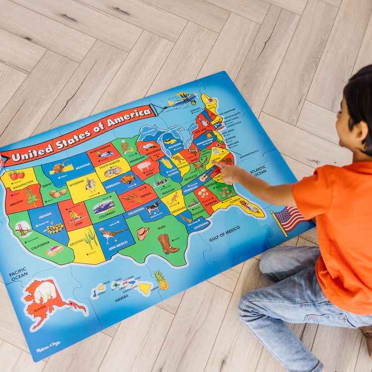 A kid playing with The Melissa & Doug USA Map Floor Puzzle - 51 Pieces (2 x 3 feet)