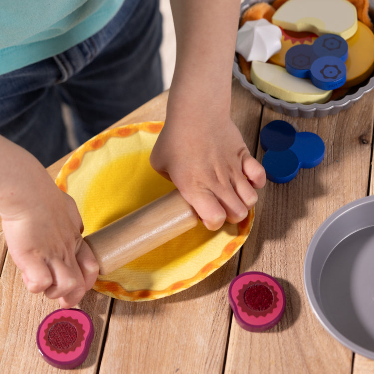 A kid playing with The Melissa & Doug Make and Bake Pies Pretend Play Food Set And Wooden Oven With Squishy Dough for Ages 3+