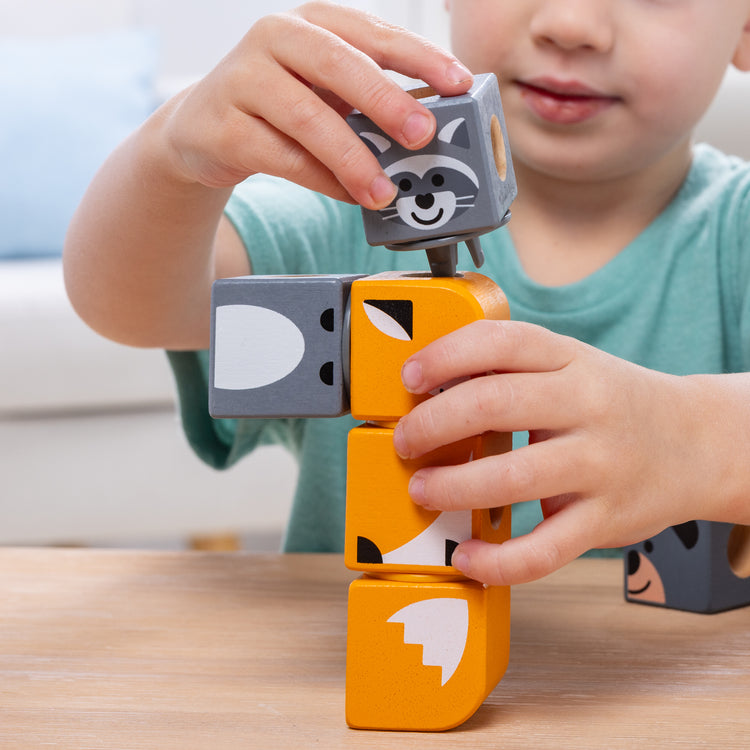 A kid playing with The Melissa & Doug Blockables™ Farm and Woodland 2-Pack Bundle Connectable Wooden Building Blocks Preschool Play Set Toy 
