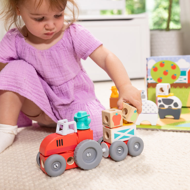 A kid playing with The Melissa & Doug Blockables™ Farm and Farm Friends 2-Pack Bundle Connectable Wooden Building Blocks Preschool Play Set Toy