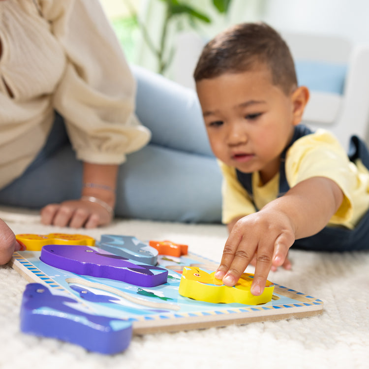 A kid playing with The Melissa & Doug Sea Creatures Ocean Wooden Chunky Puzzle - 7 Pieces