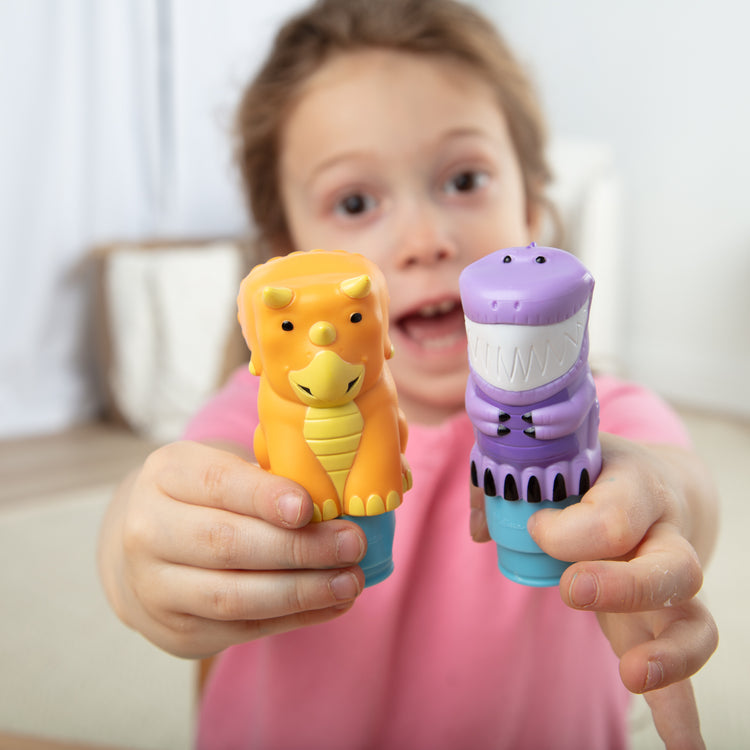A kid playing with The Melissa & Doug Sticker Wow!™ T-Rex and Triceratops Bundle: Two 24-Page Activity Pads, 2 Sticker Stampers, 900 Stickers, Arts and Crafts Fidget Toy Collectible Characters