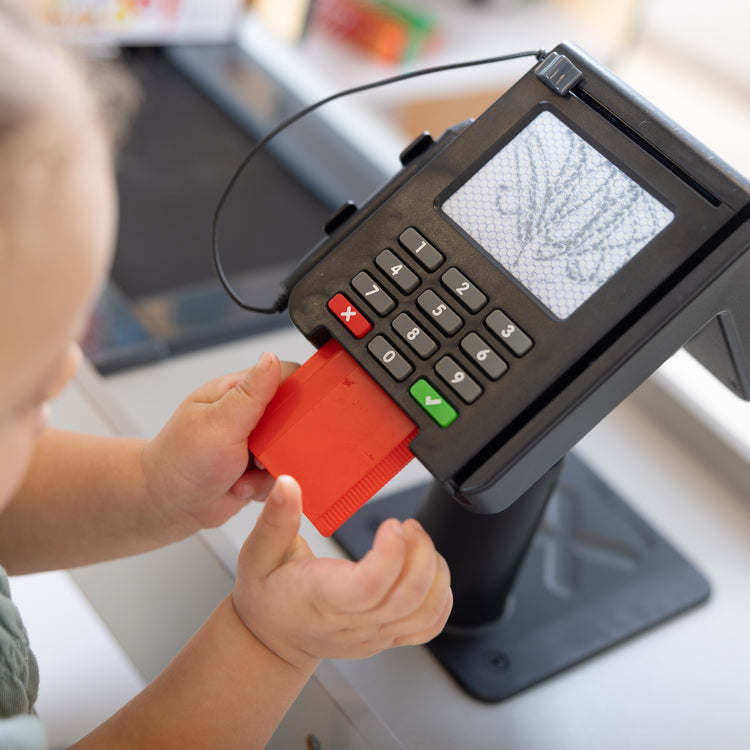 A kid playing with The Melissa & Doug Freestanding Wooden Fresh Mart Grocery Store