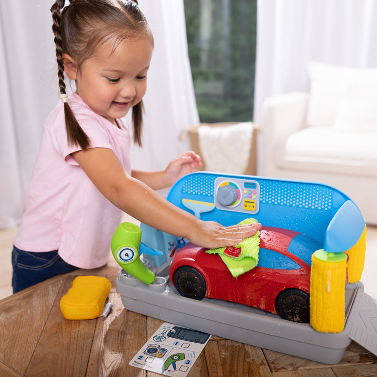 A kid playing with The Melissa & Doug Spray & Shine Car Wash Color-Changing Water Toy Play Set Boys and Girls 3+