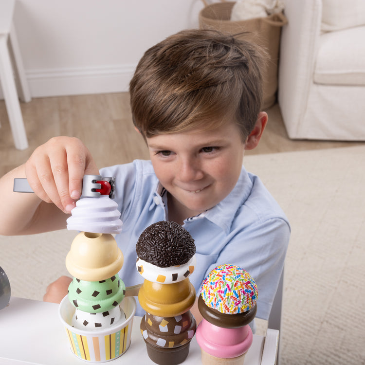 A kid playing with The Melissa & Doug Wooden Scoop and Serve Ice Cream Counter With Play Food and Accessories (28 Pcs) 
