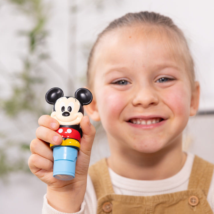 A kid playing with The Melissa & Doug Sticker WOW!™ Disney Mickey Mouse Bundle: 24-Page Activity Pad, Sticker Stamper, 500 Stickers, Mini Pad, Arts and Crafts Fidget Toy Collectible Character

