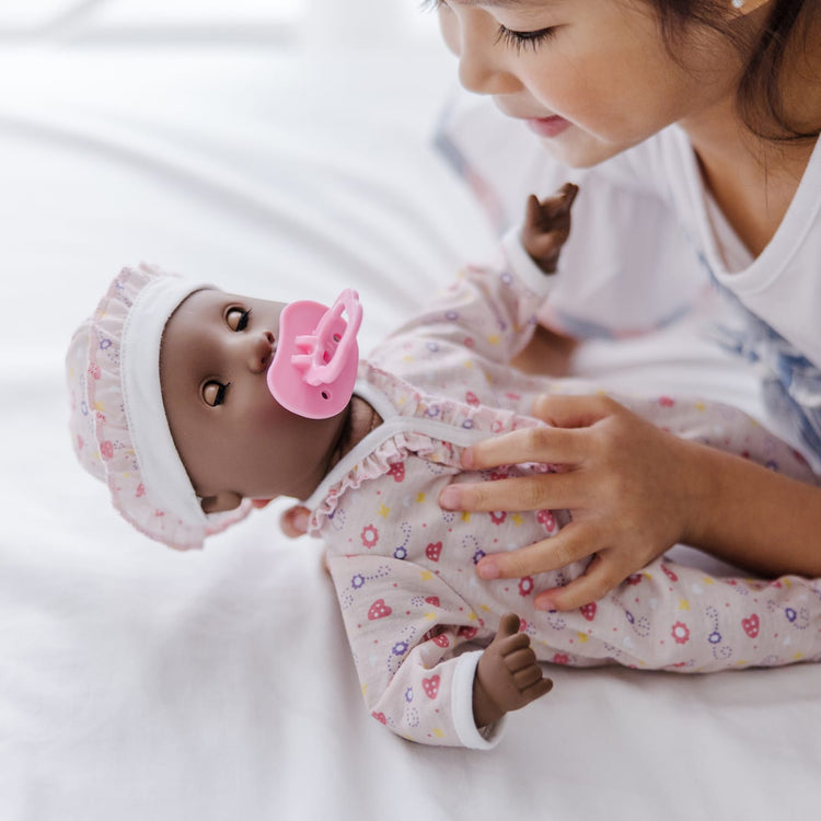 A kid playing with the Melissa & Doug Mine to Love Gabrielle 12" Poseable Baby Doll With Romper, Hat, Pacifier