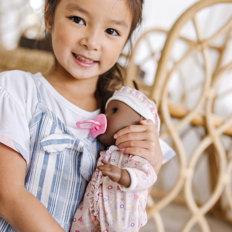 A kid playing with the Melissa & Doug Mine to Love Gabrielle 12" Poseable Baby Doll With Romper, Hat, Pacifier